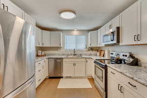 Kitchen featuring light wood-type flooring, appliances with stainless steel finishes, sink, and white cabinets