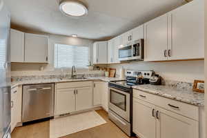 Kitchen featuring sink, stainless steel appliances, light hardwood / wood-style floors, and white cabinets