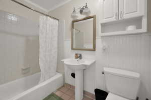 Bathroom with tile patterned flooring, ornamental molding, toilet, and shower / bath combo with shower curtain