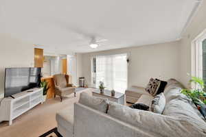 Living room featuring a textured ceiling, light colored carpet, and ceiling fan