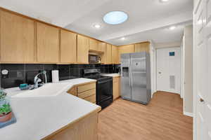 Kitchen with sink, light hardwood / wood-style flooring, light brown cabinetry, and black appliances