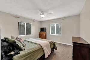 Carpeted bedroom with a textured ceiling and ceiling fan