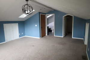 Additional living space with lofted ceiling with skylight and carpet