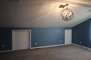 Bonus room with a notable chandelier, vaulted ceiling, a textured ceiling, and carpet