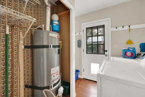 Laundry area featuring strapped water heater, wood-type flooring, and washer and dryer