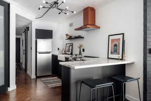 Kitchen with a barn door, freestanding refrigerator, a peninsula, range hood, and a sink