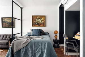 Bedroom featuring an AC wall unit and concrete floors