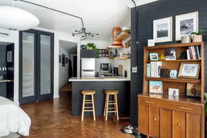 Kitchen with crown molding, fridge, a notable chandelier, a kitchen bar, and kitchen peninsula