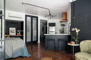 Kitchen featuring refrigerator, light countertops, a wall mounted AC, concrete floors, and wall chimney exhaust hood