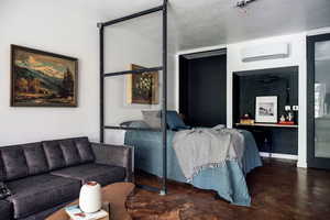 Living area with finished concrete flooring, baseboards, and a wall mounted air conditioner