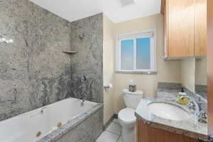 Bathroom featuring tiled tub, vanity, tile patterned flooring, and good storage.