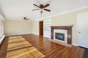 Living room featuring hardwood, ornamental molding, a tile fireplace, and ceiling fans.