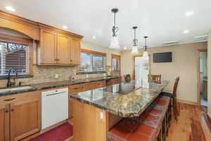 Kitchen featuring sink, dishwasher, island, and black electric stovetop.