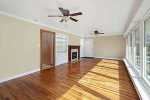 Lliving room featuring crown molding, hardwood flooring,  fireplace, and ceiling fans.