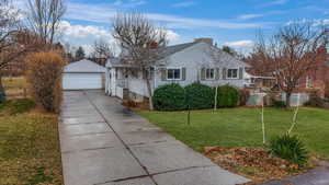 View of front of home featuring a garage, an outdoor structure, and front yard.