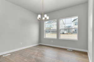 Unfurnished room featuring hardwood / wood-style flooring and a chandelier