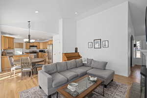 Living room featuring high vaulted ceiling, a chandelier, and light hardwood / wood-style floors