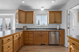 Kitchen featuring dishwasher, sink, light wood-type flooring, and kitchen peninsula