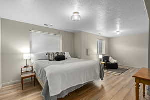 Bedroom with light hardwood / wood-style flooring and a textured ceiling