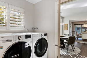 Clothes washing area featuring dark hardwood / wood-style floors, a healthy amount of sunlight, and washer and clothes dryer