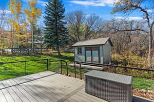 Wooden deck featuring a lawn and a shed