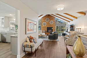 Living room featuring sink, hardwood / wood-style floors, a large fireplace, a textured ceiling, and beamed ceiling