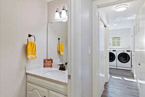 Bathroom featuring vanity, hardwood / wood-style floors, and washing machine and clothes dryer