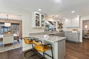 Kitchen with dark hardwood / wood-style flooring, hanging light fixtures, kitchen peninsula, and a breakfast bar