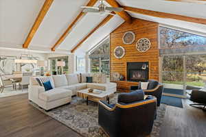 Living room with dark hardwood / wood-style flooring, a large fireplace, high vaulted ceiling, and wood walls