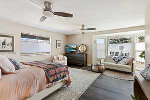 Bedroom with dark hardwood / wood-style flooring, ceiling fan, and a textured ceiling