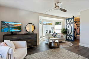 Living room featuring a barn door, dark hardwood / wood-style floors, a textured ceiling, and ceiling fan