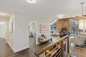 Living room featuring dark wood-type flooring, vaulted ceiling, a large fireplace, and wood walls