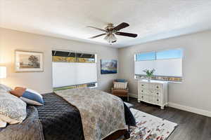 Bedroom featuring ceiling fan, dark hardwood / wood-style floors, and a textured ceiling