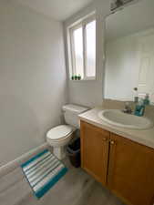 Bathroom featuring hardwood / wood-style flooring, vanity, and toilet