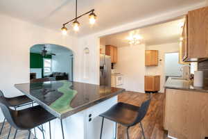 Kitchen with white electric range, a breakfast bar, sink, stainless steel fridge with ice dispenser, and kitchen peninsula