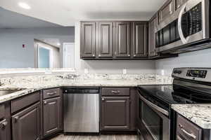 Kitchen featuring appliances with stainless steel finishes, sink, light hardwood / wood-style floors, and dark brown cabinets