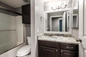 Full bathroom featuring toilet, vanity, and shower / bath combination with glass door