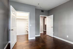 Unfurnished bedroom with a walk in closet and dark hardwood / wood-style floors