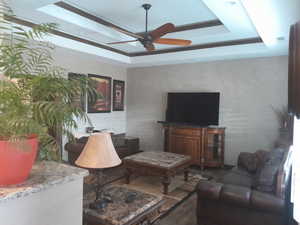 Living room featuring ceiling fan and a tray ceiling