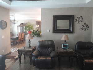 Sitting room featuring a raised ceiling, hardwood / wood-style floors, and a chandelier