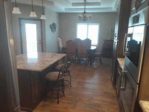 Kitchen with pendant lighting, a breakfast bar area, dark hardwood / wood-style flooring, and light stone counters