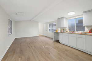 Kitchen with white cabinetry, sink, and light hardwood / wood-style flooring