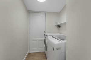 Laundry room featuring washing machine and dryer and light wood-type flooring