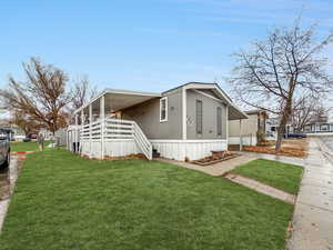 View of side of property featuring a lawn and a porch