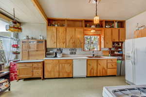 Kitchen featuring hanging light fixtures, white appliances, and sink