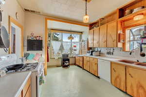 Kitchen with white appliances, decorative light fixtures, and sink