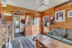 Living room with wood ceiling, wood-type flooring, and wooden walls