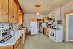 Kitchen featuring sink, white appliances, and decorative light fixtures