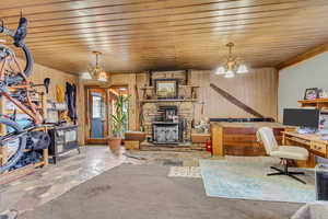 Interior space with an inviting chandelier, light colored carpet, wooden walls, and wooden ceiling