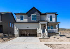 View of front of home featuring driveway, a porch, and a garage